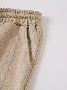 Detailopname van beige herenshorts met jacquardpatroon, elastische taille en zak.