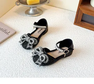 Close-up of elegant black children's princess shoes with pearl bow and strap details