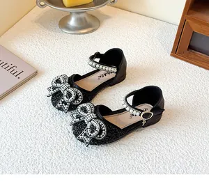 Detailed view of girls black glitter Mary Jane shoes with pearl rhinestone bow