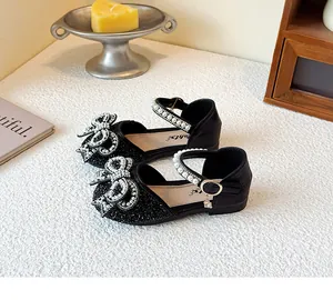 Detailed view of black glitter girl's dress shoes with pearl bow and rhinestone accents.