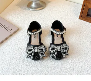 Close-up of black girl's princess shoes with rhinestone bow and pearl strap decoration