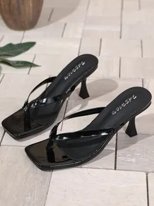 Nahaufnahme eleganter schwarzer Lackleder-Zehenstegsandalen mit modischen Pfennigabsätzen.