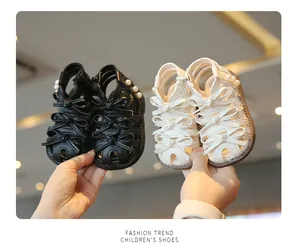 Detailaufnahme von schwarzen und weißen Baby-Prinzessinnen-Sandalen mit Schleifen.