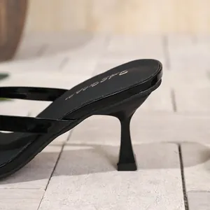 Nahaufnahme des eleganten schwarzen Lackleder-Stilettoabsatzes einer Zehensandale