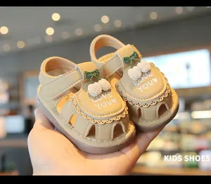 Dettaglio di sandali beige per neonata con decoro a ciliegia e ricamo Love You