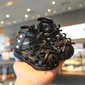 Elegante schwarze Mädchen-Römersandalen mit dekorativen Schleifen und Perlenakzenten.