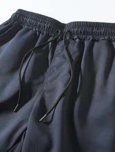 Gros plan sur la taille élastique et le cordon de serrage d'un short tissé marine.