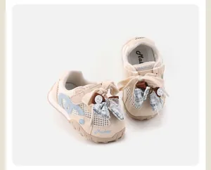 Detailed view of breathable beige baby girl mesh sneakers with blue ribbon bows