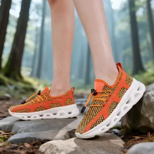 Lightweight orange outdoor sneakers with breathable mesh and chunky hollow soles for hiking.