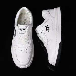 Primer plano de elegantes zapatillas de cuero blanco para hombre sobre fondo oscuro.