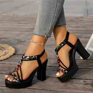 Detalle de sandalias negras con plataforma, correas trenzadas de colores y joyas
