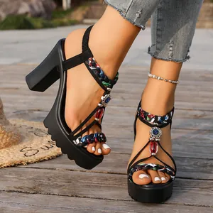 Detalle de las tiras trenzadas y joyas en las sandalias negras con plataforma