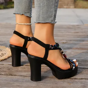 Detalle lateral de las tiras trenzadas de colores y tacón grueso en sandalias negras