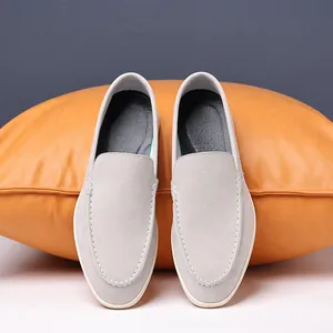 Top view detail of men's breathable grey suede loafers against a stylish orange cushion
