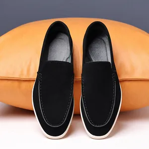 Top view of men's black suede loafers resting on a textured orange cushion.