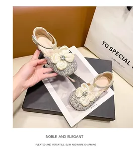 Close-up of glittery girls' princess sandals with elegant cream flower and rhinestone