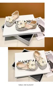 Detailed view of silver glitter girl's shoes with large elegant cream satin flower