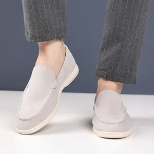 Detailed view of grey suede loafers worn with striped trousers in a clean setting