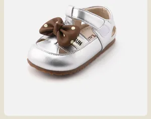 Detail view of silver toddler girl shoes with a brown polka-dot bow accent.