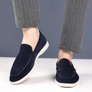 Close-up detail shot of navy blue suede loafers worn with grey striped formal trousers.