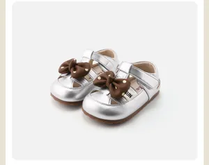 Silver toddler walking shoes with decorative brown polka-dot bows and Velcro strap details.