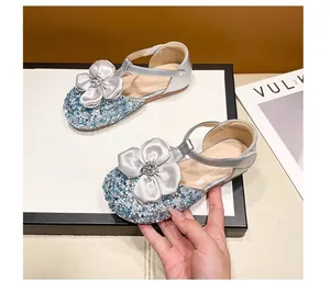 Detailed view of sparkly silver girls' princess shoes with sequin and satin flower accents.