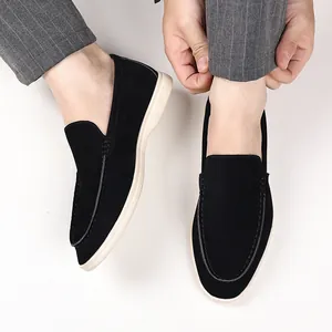Close-up of classic black suede loafers worn with grey pinstripe trousers in a casual setting