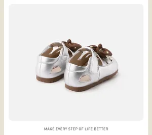 Rear view of silver toddler girl shoes featuring a brown bow and soft rubber sole