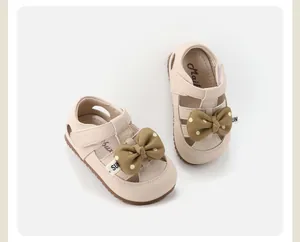 Close-up detail of cream toddler girl walking sandals featuring a cute polka dot bow