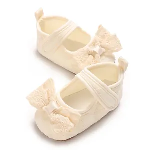 Close-up of cream baby princess shoes with lace bow details and soft walking soles.