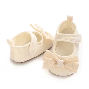 Close-up of cream lace baby shoes with decorative butterfly bow and velcro strap