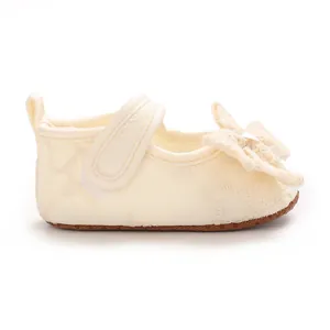 Close-up detail of cream baby girl princess shoes with a soft bow and floral embroidery