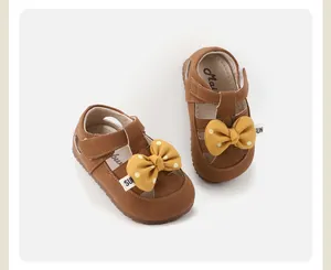 Close-up of toddler girls brown walking shoes with yellow polka-dot bows and soft soles.