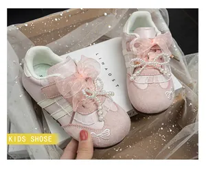 Close-up of pink girls sneakers with pearl bow and lace ribbon details