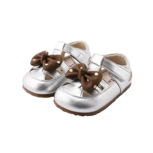 Silver toddler girl Mary Jane shoes with brown bow accents and soft non-slip soles.
