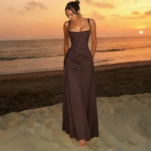 Elegant brown ruched maxi dress with square neck shown in a sunset beach setting