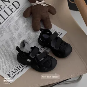 Close-up detail of black kids' closed-toe sandals with anti-slip design and velcro.