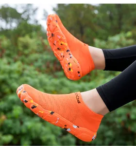 Close-up of orange breathable water shoes with mesh texture and splash pattern sole.