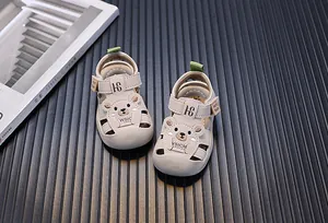 Nahaufnahme beiger Kleinkindsandalen mit süßem Bären-Design und weichen Sohlen.