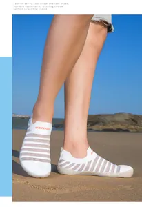 Detailed side view of white striped water shoes worn on beach sand under bright sunlight