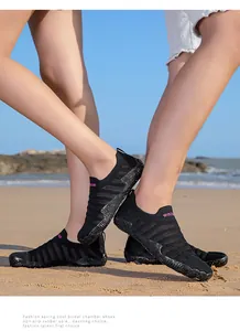 Detail view of black mesh water shoes with non-slip soles on a sandy beach