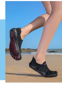 Professional barefoot water shoes with flexible grip sole shown on a sandy beach background
