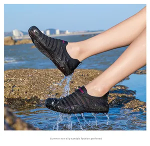 Side view of non-slip black wading shoes worn while splashing in ocean water beach scene