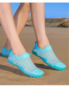 Light blue mesh water shoes worn on a sandy beach, showcasing breathable stripes.