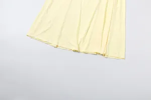 Detail view of the hemline of a solid pale yellow high-waisted pleated dress for women