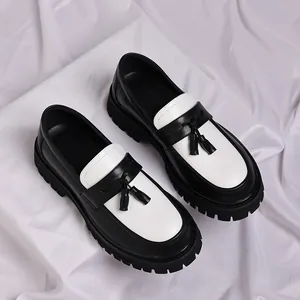 Λεπτομέρεια από ασπρόμαυρα loafers με χοντρή σόλα και κομψές φούντες για άνδρες