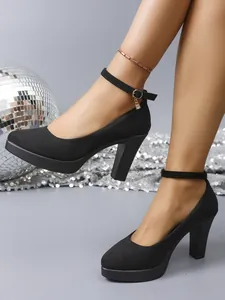 Detailed view of black suede chunky heel pumps with ankle straps and round toe