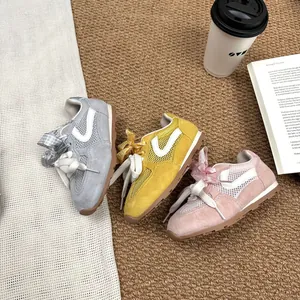 Detail shot of girls' mesh sneakers with ribbon bow laces in grey yellow and pink