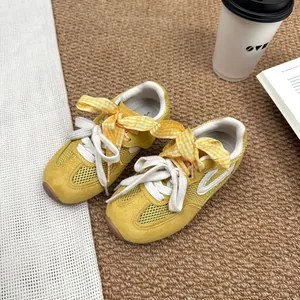 Detail view of yellow mesh girl sneakers featuring cute checkered bow and non-slip sole.