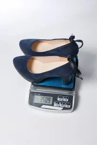 Weight measurement of navy blue suede chunky heel pumps displayed on a digital scale
